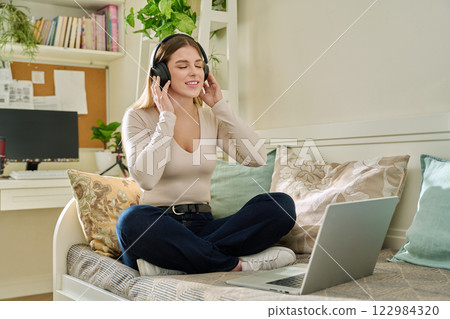 Happy relaxed young woman in headphones with closed eyes listening to audio text, music Happy relaxed young woman in headphones with closed eyes listening to audio text, music 122984320