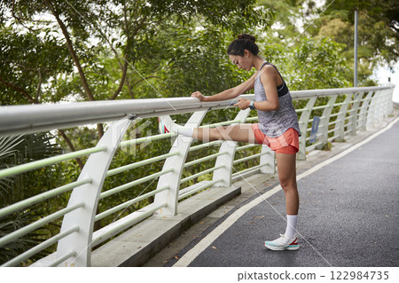 young asian woman pressing legs before exercising outdoors 122984735