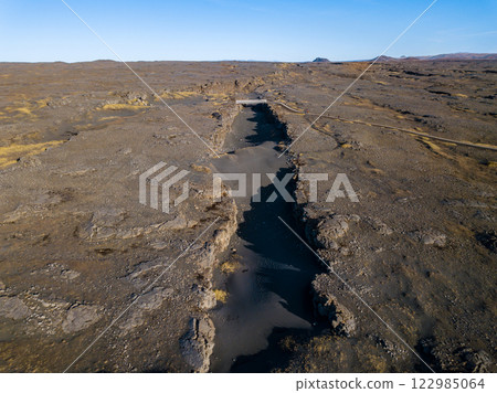 Aerial of the bridge connecting the north american and eurasian tectonic plates at Reykjanes, showcasing the dramatic rift between two major geological boundaries 122985064