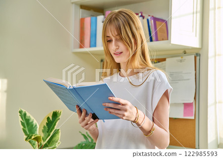 Young teenage female reading book, novel, fiction educational literature at home Young teenage female reading book, novel, fiction educational literature at home 122985593