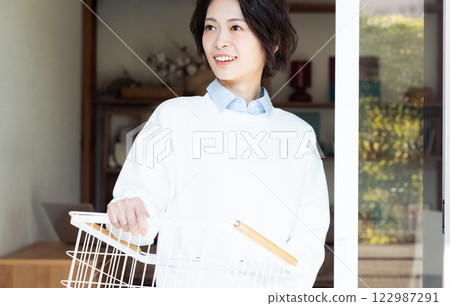 女人拿著洗衣籃，看著窗外 122987291