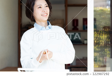 女人拿著洗衣籃，看著窗外 122987292