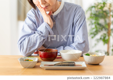 A middle-aged woman worried about her Japanese breakfast A middle-aged woman worried about her Japanese breakfast 122987864