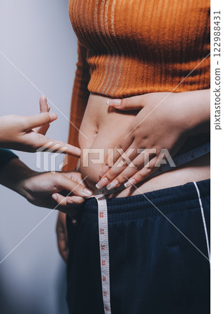 Asian Woman Pinching Her Belly Fat With Left Hand 122988431
