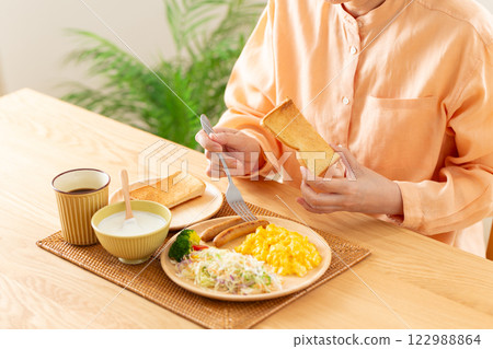Hands of a middle-aged woman eating toast for a Western-style breakfast Hands of a middle-aged woman eating toast for a Western-style breakfast 122988864
