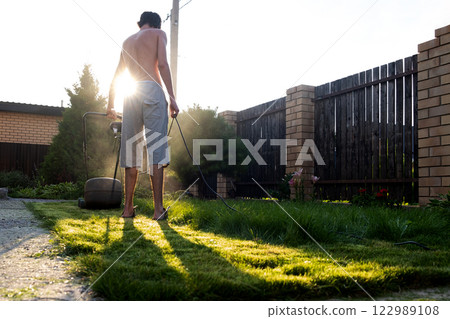 Freshly cut thick grass on the lawn, sunny day at sunset, low angle view. Green grass in the backyard, electric lawn mower 122989108