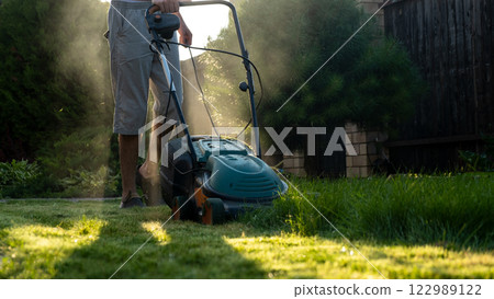Freshly cut thick grass on the lawn, sunny day at sunset, low angle view. Green grass in the backyard, electric lawn mower 122989122
