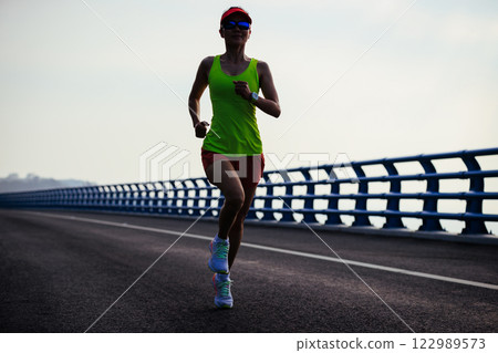 Fitness woman runner running on seaside bridge 122989573