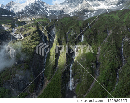 Aerial view of beautiful high altitude snow capped mountain and waterfall landscape Aerial view of beautiful high altitude snow capped mountain and waterfall landscape 122989755