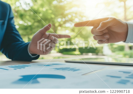 Two men are pointing at a piece of paper with graphs on it, serious and focused 122990718