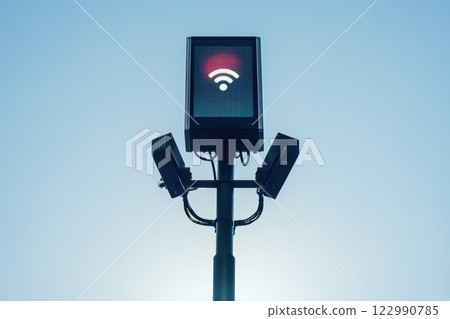 Wireless Signal Indicator with Red Light and Surveillance Cameras on a Pole Against Blue Sky Wireless Signal Indicator with Red Light and Surveillance Cameras on a Pole Against Blue Sky 122990785