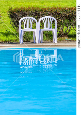 Outdoor pool water surface and white chairs 122991110