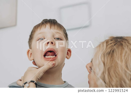 boy practicing speech therapy exercises while looking at in bright educational office with female therapist, concept of childhood development 122991524