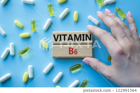 Vitamin B6 symbol. Concept word Vitamin B6 on wooden blocks. Beautiful blue background with pills. Doctor Hand. Medicine and Vitamin B6 concept. Copy space 122991564
