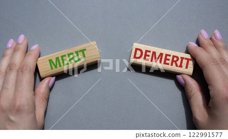 Merit or Demerit symbol. Concept word Merit or Demerit on wooden blocks. Businessman hand. Beautiful grey background. Business and Merit or Demerit concept. Copy space 122991577