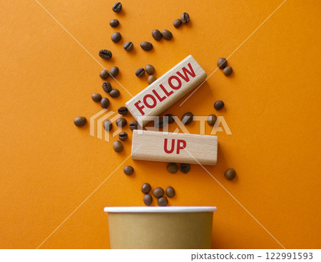 Follow up symbol. Concept word Follow up on wooden blocks. Beautiful orange background with coffee cup. Business and Follow up concept. Copy space 122991593