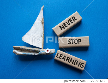 Never stop Learning symbol. Concept words Never stop Learning on wooden blocks. Beautiful blue background with boat. Business concept and Never stop Learning. Copy space. 122991612