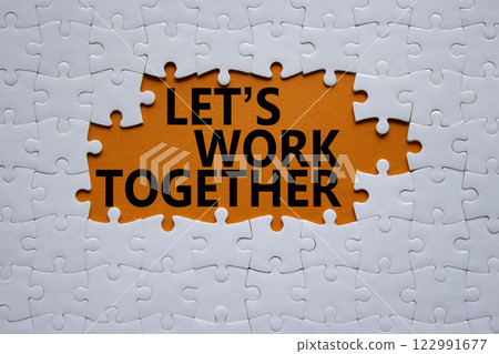 Lets work together symbol. Concept words Lets work together on white puzzle. Beautiful orange background Business and Lets work together concept. Copy space. 122991677