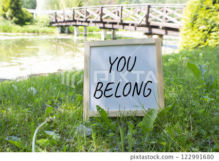 You belong symbol. White Blackboard with words You belong. Beautiful meadow background with bridge. Business and You belong concept. Copy space. You belong symbol. White Blackboard with words You belong. Beautiful meadow background with bridge. Business and You belong concept. Copy space. 122991680