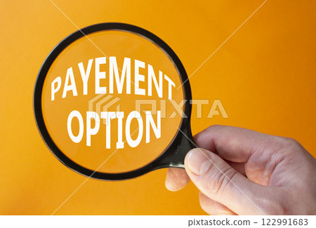 Payment Options symbol. Concept words Payment Options on magnifying glass. Businessman hand. Beautiful orange background. Business and Payment Options concept. Copy space. 122991683