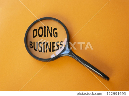 Doing Business symbol. Magnifying Glass with Concept word Doing Business. Beautiful orange background. Business and Doing Business concept. Copy space 122991693