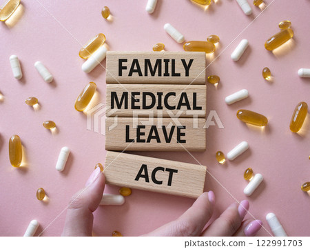 Family Medical Leave Act symbol. Concept word Family Medical Leave Act on wooden blocks. Businessman hand. Beautiful pink background with pills. Medicine concept. Copy space Family Medical Leave Act symbol. Concept word Family Medical Leave Act on wooden blocks. Businessman hand. Beautiful pink background with pills. Medicine concept. Copy space 122991703