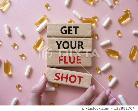 Get your Flue Shot symbol. Concept word Get your Flue Shot on wooden blocks. Businessman hand. Beautiful pink background with pills. Medicine Get your Flue Shot concept. Copy space Get your Flue Shot symbol. Concept word Get your Flue Shot on wooden blocks. Businessman hand. Beautiful pink background with pills. Medicine Get your Flue Shot concept. Copy space 122991704