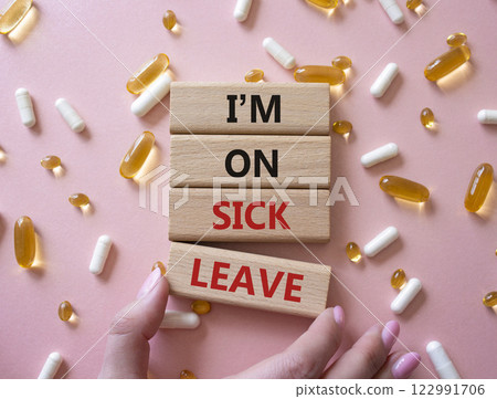 Sick leave symbol. Concept word I am on sick leave on wooden blocks. Businessman hand. Beautiful pink background with pills. Medicine and I am on sick leave concept. Copy space 122991706