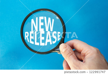 New Release symbol. Concept word New Release on magnifying glass. Beautiful blue background. Businessman hand. Business and New Release concept. Copy space. 122991747