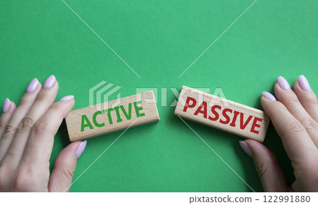Active or Passive symbol. Concept word Active or Passive on wooden blocks. Businessman hand. Beautiful green background. Business and Active or Passive concept. Copy space Active or Passive symbol. Concept word Active or Passive on wooden blocks. Businessman hand. Beautiful green background. Business and Active or Passive concept. Copy space 122991880
