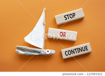 Stop or Continue symbol. Concept words Stop or Continue on wooden blocks. Beautiful orange background with boat. Business concept and Stop or Continue. Copy space. Stop or Continue symbol. Concept words Stop or Continue on wooden blocks. Beautiful orange background with boat. Business concept and Stop or Continue. Copy space. 122991922