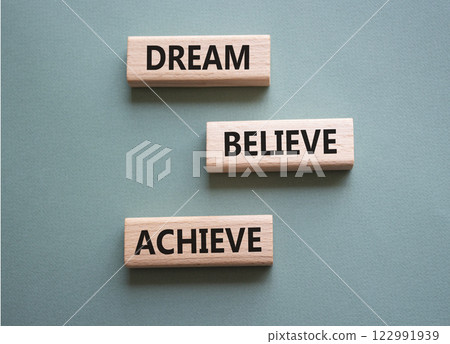 Dream Believe Achieve symbol. Wooden blocks with words Dream Believe Achieve. Beautiful grey green background. Business and Dream Believe Achieve concept. Copy space. 122991939
