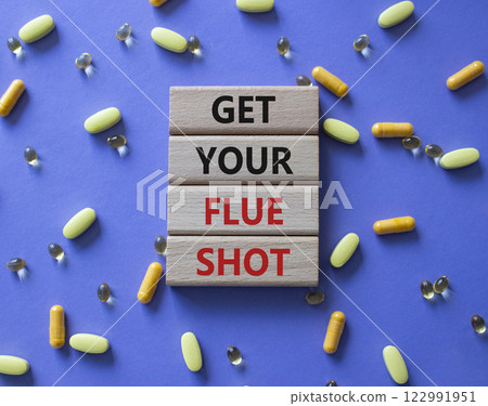 Get your Flue Shot symbol. Concept word Get your Flue Shot on wooden blocks. Beautiful purple background with pills. Medicine Get your Flue Shot concept. Copy space 122991951