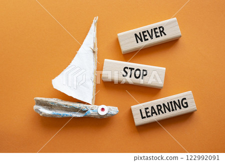 Never stop Learning symbol. Concept words Never stop Learning on wooden blocks. Beautiful orange background with boat. Business concept and Never stop Learning. Copy space. 122992091