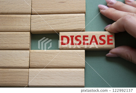 Disease symbol. Concept word Disease on wooden blocks. Doctor hand. Beautiful grey green background. Medicine and Disease concept. Copy space. 122992137