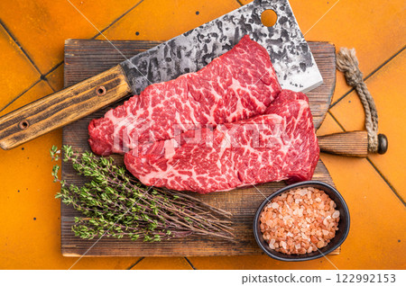 Fresh raw Denver steak, showcasing its marbled texture and rich color, perfect for grilling or pan-searing to create a flavorful meal. orange background. top view Fresh raw Denver steak, showcasing its marbled texture and rich color, perfect for grilling or pan-searing to create a flavorful meal. orange background. top view 122992153