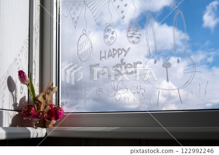 HAPPY EASTER text on creative painted window with white marker. Easter bunny rabbit decoration on big clear window. Springtime idea home decoration 122992246