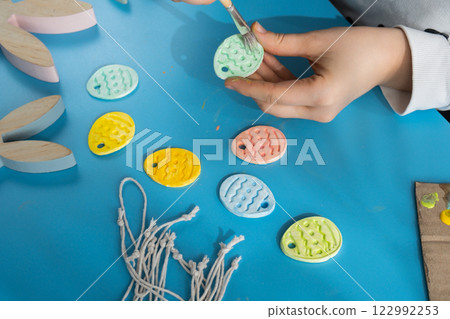 Master class of coloring Creator is using white air dry clay for making decor to EASTER holiday. Creating hobby recreation activity that involves fingers. DIY crafting 122992253