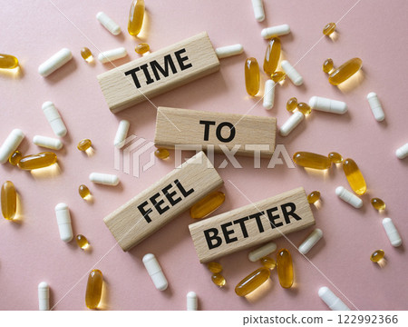 Time to feel better symbol. Concept word Time to feel better on wooden blocks. Beautiful pink background with pills. Health concept. Copy space Time to feel better symbol. Concept word Time to feel better on wooden blocks. Beautiful pink background with pills. Health concept. Copy space 122992366