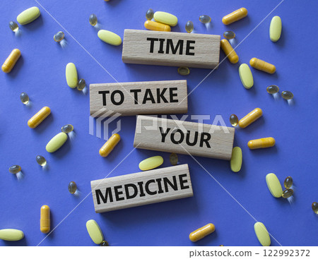 Time to take your Medicine symbol. Concept word Time to take your Medicine on wooden blocks. Beautiful purple background with pills. Health concept. Copy space 122992372