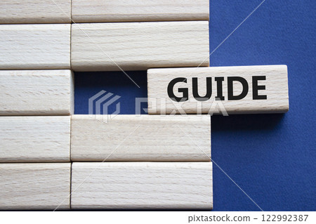 Guide symbol. Concept word Guide on wooden blocks. Beautiful deep blue background. Business and Guide concept. Copy space. 122992387