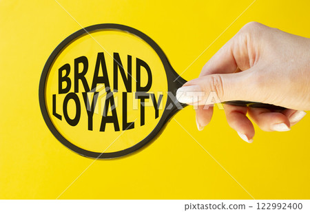 Brand Loyalty symbol. Concept word Brand Loyalty on magnifying glass. Beautiful yellow background. Businessman hand. Business and Brand Loyalty concept. Copy space. Brand Loyalty symbol. Concept word Brand Loyalty on magnifying glass. Beautiful yellow background. Businessman hand. Business and Brand Loyalty concept. Copy space. 122992400