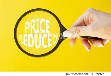 Price reduced symbol. Magnifying Glass with Concept word Price reduced. Beautiful yellow background. Businessman hand. Business and Price reduced concept. Copy space Price reduced symbol. Magnifying Glass with Concept word Price reduced. Beautiful yellow background. Businessman hand. Business and Price reduced concept. Copy space 122992402