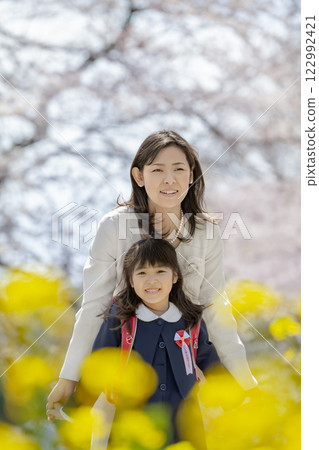 一位母親和她剛出生的女兒在盛開著櫻花和油菜花的公園裡玩耍 122992421