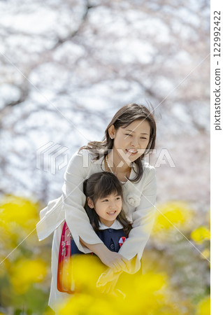 一位母親和她剛出生的女兒在盛開著櫻花和油菜花的公園裡玩耍 122992422