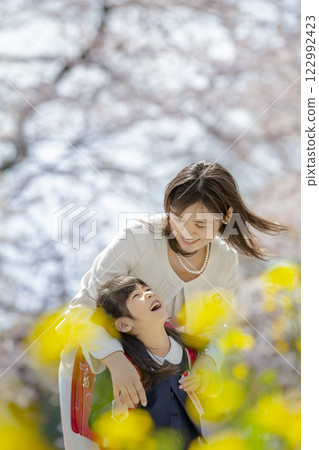 A mother and her new daughter enjoying a park filled with cherry blossoms and rape blossoms 122992423