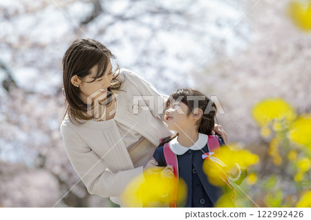 一位母親和她剛出生的女兒在盛開著櫻花和油菜花的公園裡玩耍 122992426