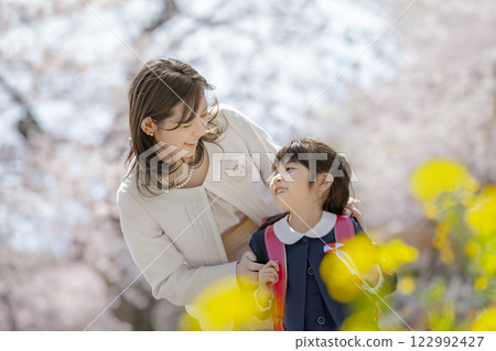 一位母親和她剛出生的女兒在盛開著櫻花和油菜花的公園裡玩耍 122992427