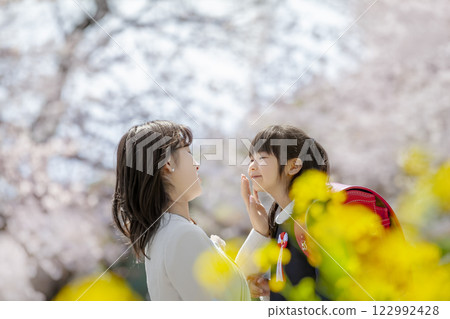 一位母親和她剛出生的女兒在盛開著櫻花和油菜花的公園裡玩耍 122992428