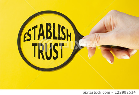 Establish trust symbol. Magnifying Glass with Concept word Establish trust. Beautiful yellow background. Businessman hand. Business and Establish trust concept. Copy space Establish trust symbol. Magnifying Glass with Concept word Establish trust. Beautiful yellow background. Businessman hand. Business and Establish trust concept. Copy space 122992534